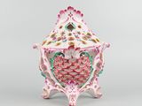a pink and green vase sitting on top of a white table
