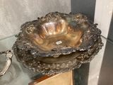 un bol en argent posé sur une table en verre, à côté de deux cuillères en argent