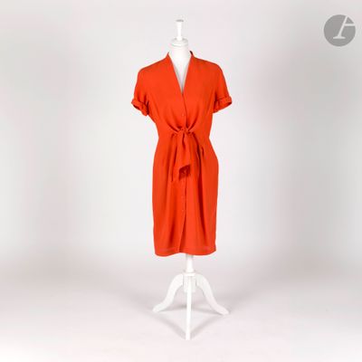 une robe orange posée sur un présentoir à mannequin, sur fond blanc