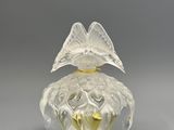 a clear glass perfume bottle with a bird on top of it