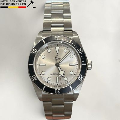 the watch is on a metal bracelet on a white surface