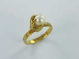 gros plan d'une bague en or contenant une perle