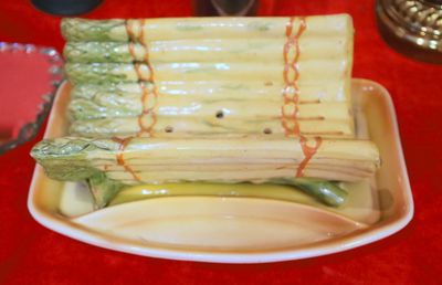 a plate of asparagus wrapped in plastic wrap on a red table cloth