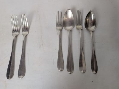 five forks and two spoons on a white table