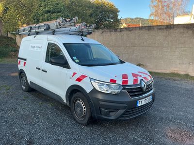 La camionnette blanche est garée sur un parking, avec une échelle posée sur le toit.