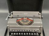 an old typewriter with a case on it sitting on a table