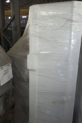 Des cartons contenant des matelas sont empilés sur des palettes dans un entrepôt