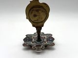 a small clock that is on a stand on a white surface
