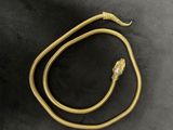 a gold snake necklace on a black background
