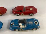 four toy cars are lined up in a row on a white surface