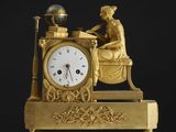 une horloge dorée représentant une femme assise à un bureau