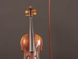 un vieux violon posé sur une table en bois, à côté d'un archet