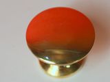 a red and gold knob on a white surface