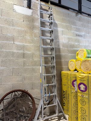 a ladder that is leaning against a wall next to a pile of boxes