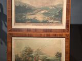 two paintings of a man and a woman in a landscape on a table