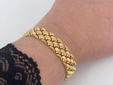 the woman is wearing a gold bracelet with a chain on her wrist