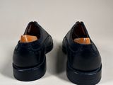 a pair of black leather shoes on a white surface
