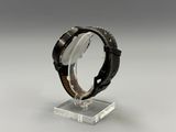 a close up of a watch on a clear stand on a gray surface