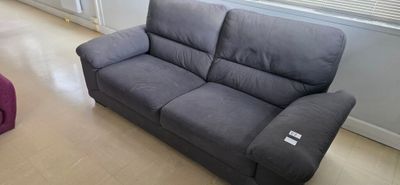 a grey couch sitting in a living room next to a window