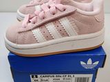 une paire de baskets Adidas roses et blanches dans une boîte bleue