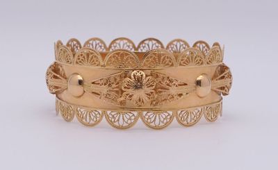 gros plan d'un bracelet en or sur une surface blanche