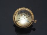 a gold clock on a black surface with a black background