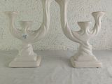 two white vases sitting on a table with a white background