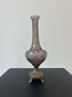 a glass vase on a black table with a white wall in the background