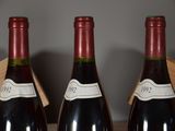 three bottles of red wine are lined up on a shelf
