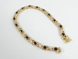 a gold bracelet with black and white stones on a white background