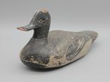 un vieux canard en bois posé sur une surface blanche