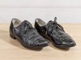 pair of black leather shoes with laces on a wooden surface