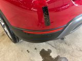 the rear end of a red car with a sticker on it ' s bumper