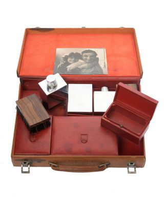 a red suitcase with a note pad and other items in it