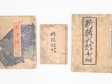trois vieux livres portant des inscriptions en caractères asiatiques, posés les uns à côté des autres