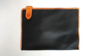 une image représentant un portefeuille noir et orange posé sur une surface blanche
