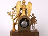 a gold clock with an angel on top of it