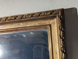 a gold framed mirror hanging on a wall next to a white wall