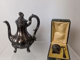 a silver tea pot and a gold box on a glass table