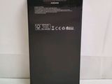 the back of a black samsung phone sitting on top of a white surface