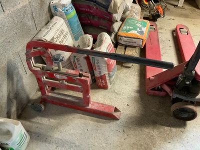 un diable rouge garé à côté d'un tas d'objets