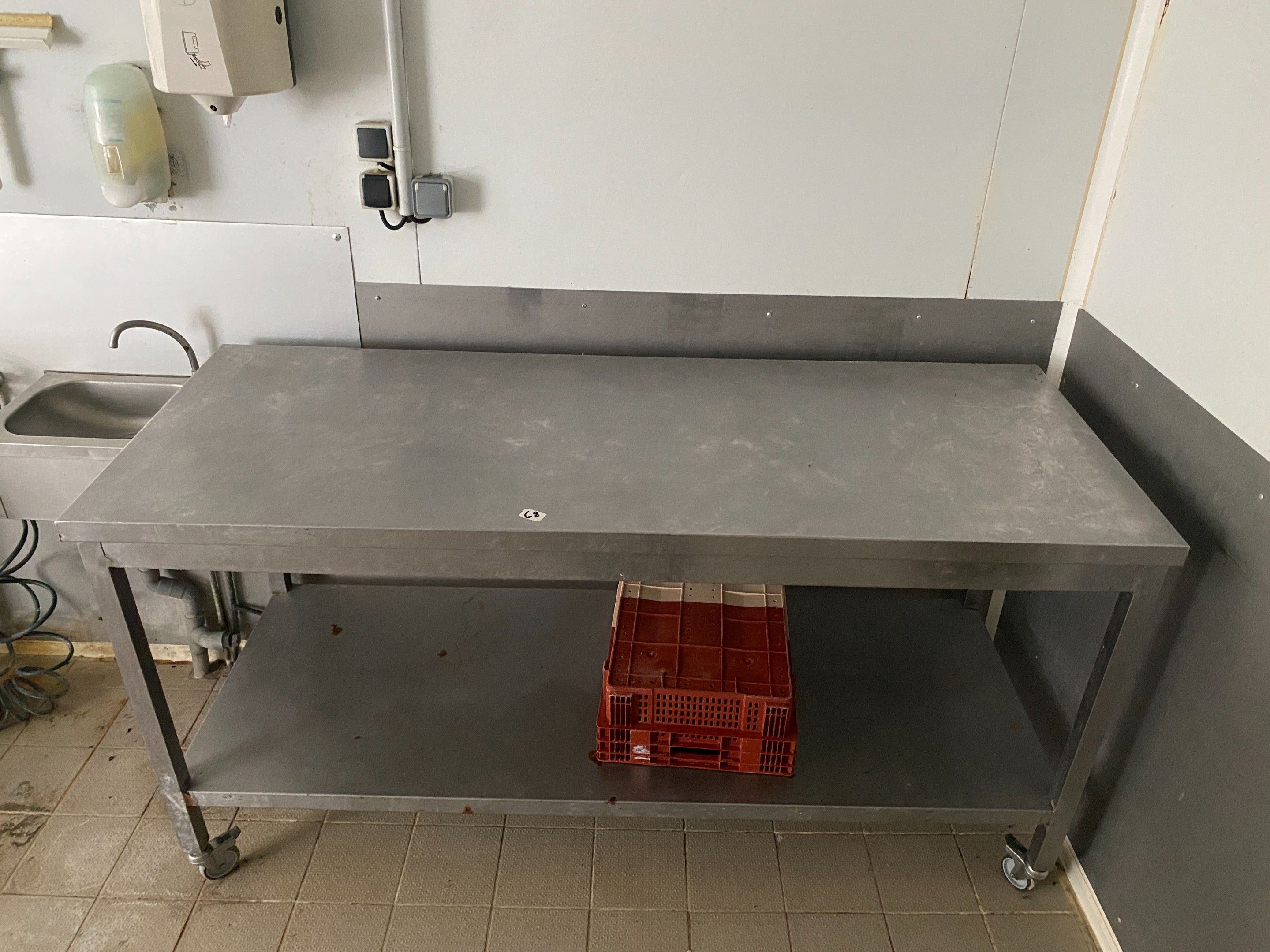 Une table rectangulaire en acier à tablette médiane, sur rou…