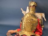 a statue of a man dressed in armor sitting on a bench