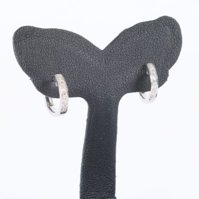 a pair of silver hoop earrings on a black stand