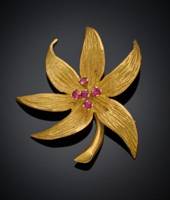 un gros plan sur une broche en forme de fleur en or sertie de pierres roses