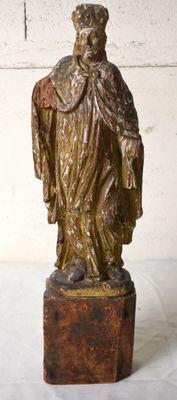 une statue représentant un homme debout sur un bloc de bois