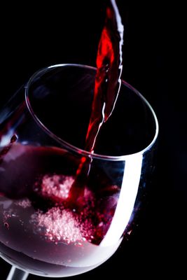 un verre de vin rouge que l'on verse dans un verre à vin