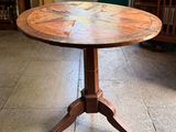 a wooden table with a circular top on a tile floor
