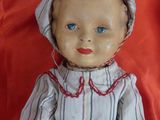 a doll that is sitting on a red cloth