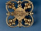 a close up of a gold brooch on a blue background